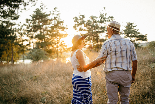 Caregiver resources Two adults walking near a field at sunset.